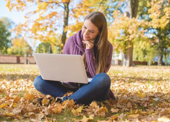Smiling Woman Using Laptop Sitting on Ground Alone