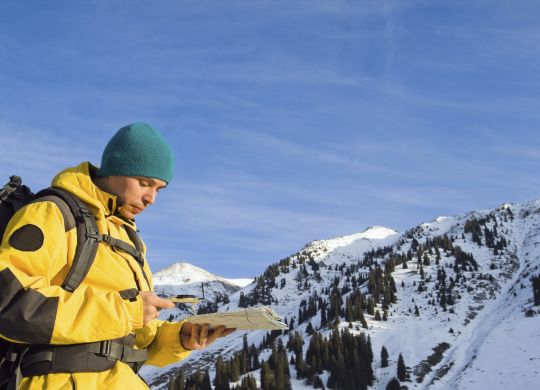 Climbing young adult with map and compass