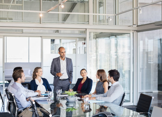 Human resource manager training people about company and future prospects. Group of businesspeople sitting in meeting room and listening to the speaker. Leader man training his work group in a conference room.