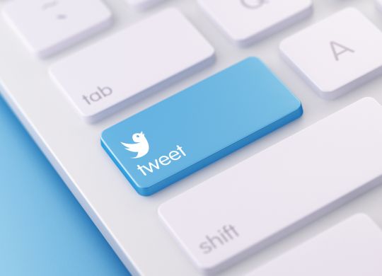 High quality 3d render of a modern keyboard with tweet button on a blue background and copy space. The tweet keyboard button has a text  and an icon on it. The tweet keyboard button is  in focus, Horizontal composition with copy space.