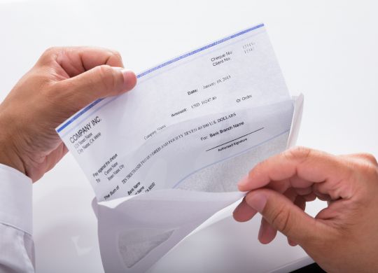 Close-up of a businessman's hand opening envelope with paycheck