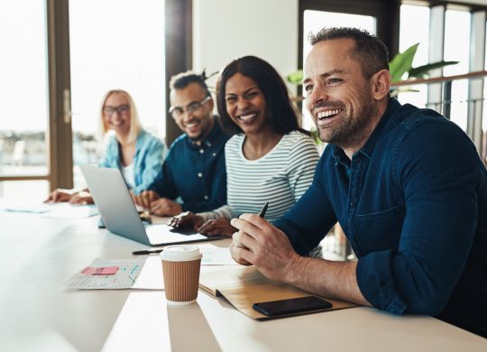 Diverse group of young businesspeople laughing while sitting together in a row at an office desk during a meeting (Diverse group of young businesspeople laughing while sitting together in a row at an office desk during a meeting, ASCII, 114 components