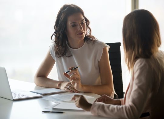 Two diverse serious businesswomen discussing business project working together in office, serious female advisor and client talking at meeting, focused executive colleagues brainstorm sharing ideas (Two diverse serious businesswomen discussing busines